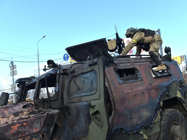 An Ukrainian Territorial Defence fighter takes the automatic grenade launcher from a destroyed Russian infantry mobility vehicle GAZ Tigr after the fight in Kharkiv. Picture: AFP