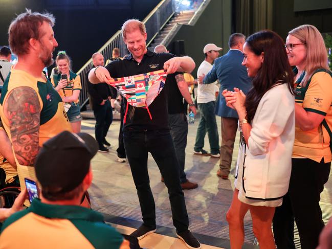 Prince Harry receives a pair of Speedos from the Australian team as a delighted Meghan Markle watches on. Picture: Getty Images for the Invictus Games Foundation