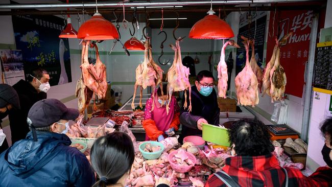 People wearing protective face masks shop at wet market stall in Shanghai, China. Picture: Noel Celis/AFP