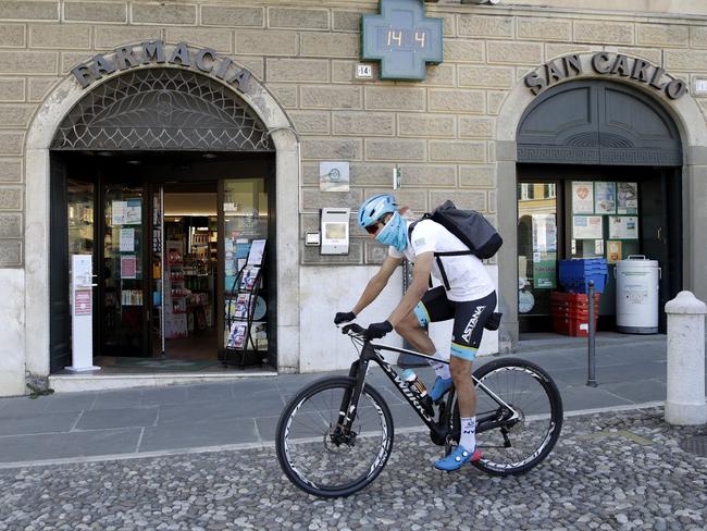 Italian professional cyclist Davide Martinelli rides his bike after collecting medicine at a pharmacy to be delivered to residents in Rovato, near Brescia in northern Italy. Picture: AP/Luca Bruno