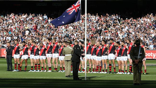 Collingwood and Essendon players stand for The Last Post. Picture: George Salpigtidis