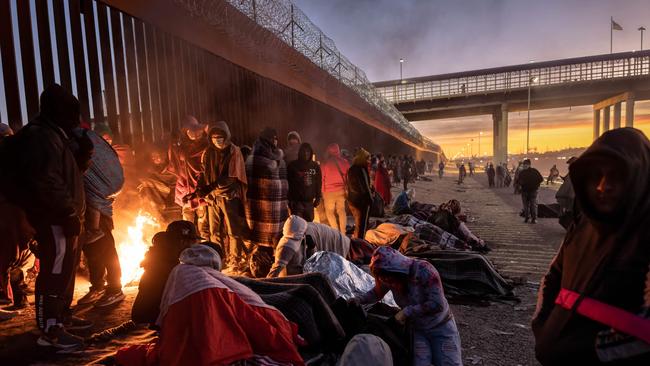 Immigrants warm to a fire at dawn after spending the night outside next to the U.S.-Mexico border fence on December 22 in El Paso, Texas.