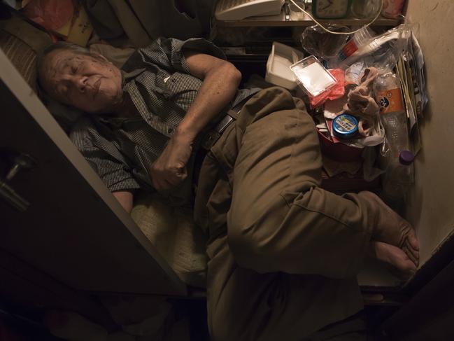 In this Thursday, March 28, 2017 photo, Cheung Chi-fong, 80, sleeps in his tiny "coffin home" where he cannot stretch out his legs in Hong Kong. In wealthy Hong Kong, there's a dark side to a housing boom, with hundreds of thousands of people forced to live in partitioned shoebox apartments, "coffin homes" and other "inadequate housing.(AP Photo/Kin Cheung)