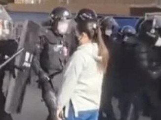 Woman faces riot police in china.