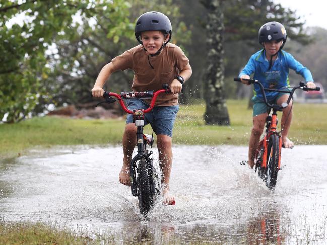 Baya Thorley ( Left , 8 fromTallebudgera ) and Harry Skews ( 7 from Boonah ) having fun riding their bikes while on holidays at Fingal as extreme weather lashes the North Coast of New South Wales.Photograph : Jason O'Brien