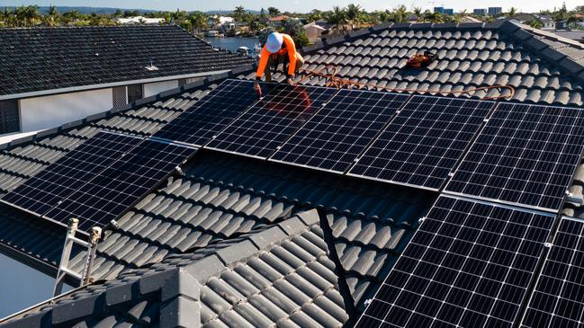 Developing Queensland - Solar panels and technician on luxury waterfront home on a sunny day.