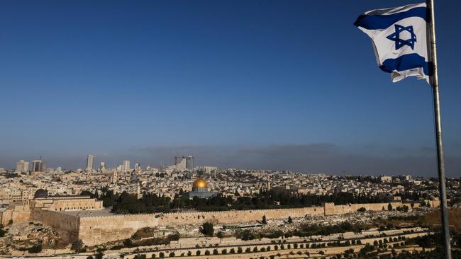 An Israeli flag flies on the Mount of Olives overlooking the city skyline in Jerusalem. It has changed hands more than 40 times throughout history, and rarely been run by the two sides now demanding ownership. Picture: Ahmad Gharabli/AFP