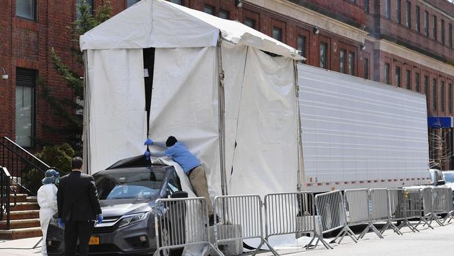 A hearse backs into a refrigerated truck to pick up dead bodies outside of the Brooklyn Hospital. Picture: AFP