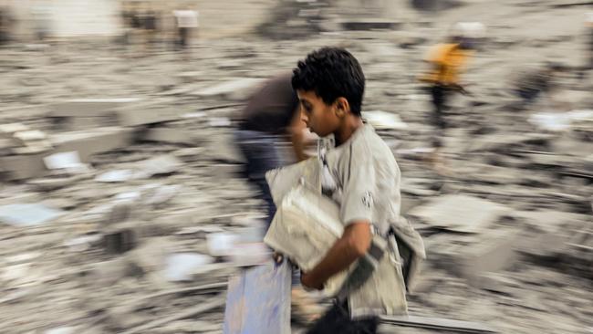 A child walks away with belongings salvaged from the rubble of a building hit in an Israeli strike on Rafah in the southern Gaza Strip. Picture: AFP