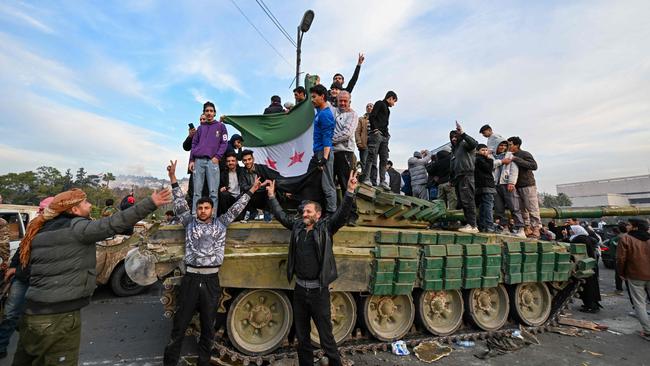 TOPSHOT - People celebrate with anti-government fighters at Umayyad Square in Damascus on December 8, 2024. Islamist-led rebels declared that they have taken Damascus in a lightning offensive on December 8, sending President Bashar al-Assad fleeing and ending five decades of Baath rule in Syria. (Photo by LOUAI BESHARA / AFP)