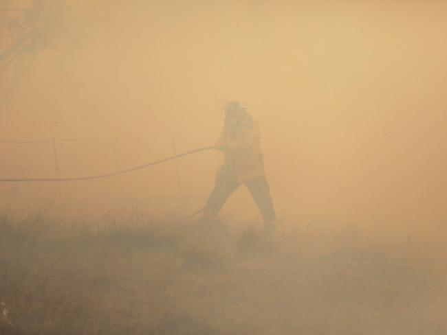 NSW RFS crews extinguish a fire that crossed the Monaro Highway, four kilometres north of Bredbo, NSW, Sunday, February 2, 2020. The Clear Range Bushfire continues to burn in soaring temperatures and forecast unpredictable wind changes. (AAP Image/Sean Davey) NO ARCHIVING