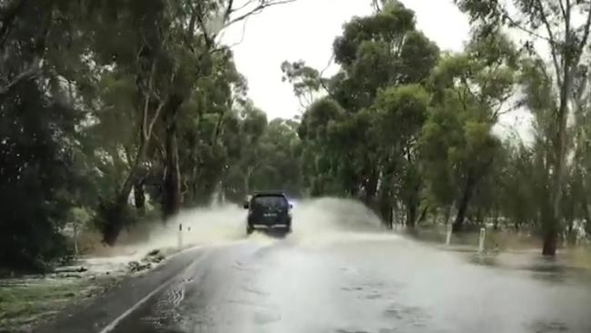 A plucky driver takes a chance with the water over Sheepwash Road near the railway crossing outside of Burrawang. Picture: Phillip Minnis