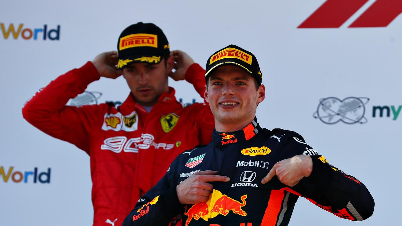 Max Verstappen celebrates his Austrian GP victory as a frustrated Charles Leclerc looks on.