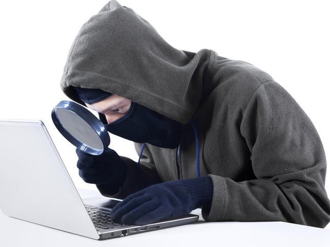 Internet Theft - a hooded man looking at computer screen using magnifying glass; scams, scammer, fraud generic