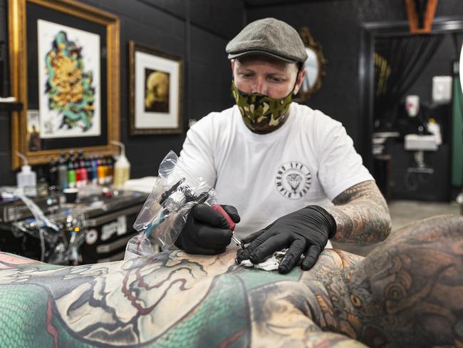 Tattoo artist Kenno works with a client in his store Diamond Eye Tattoo on September 17, 2020 in Geelong, Australia. Picture: Getty