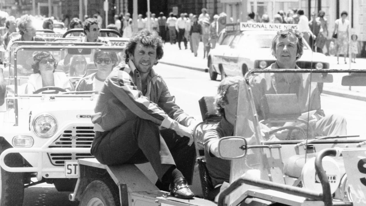 SA Sheffield Shield cricketers Ian Chappell (l) and Ken “K. G.” Cunningham sitting in open motor car during motorcade through Adelaide city streets. Filed Dec 1979. (Pic by unidentified staff photographer)