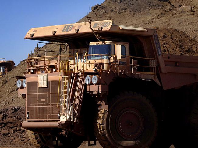 Heavy earth moving trucks at the Tom Price iron ore mine, operated by Rio Tinto Group, are lit up by the afternoon sun in Pilbara, north Western Australia on Wednesday, July 26, 2006. BHP Billiton Ltd., the world's largest mining company, is losing the support of investors and steelmakers for its proposed $128 billion takeover of Rio Tinto Group. Photographer: Jack Atley/Bloomberg News