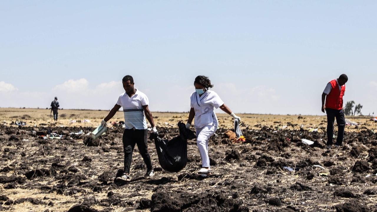 Rescue team carry collected bodies in bags at the crash site. Picture: AFP 