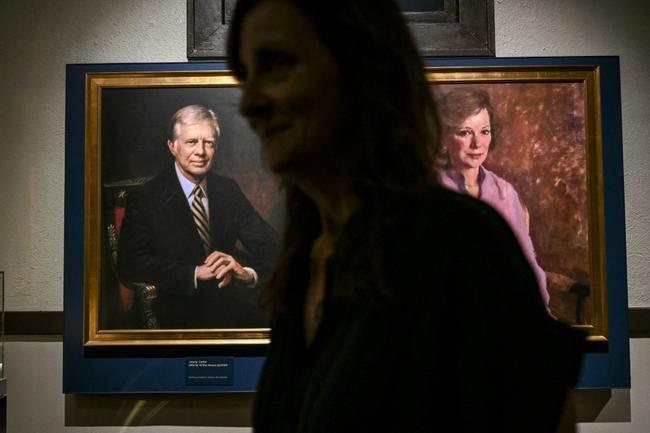 A person walks past portraits of former US president Jimmy Carter and former first lady Rosalynn Carter in Plains, Georgia