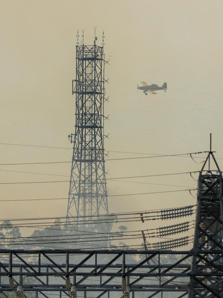 Firefighting aircraft and Firefighters defend Power infrastructure from an out of control fire in Berrimah. Picture: Glenn Campbell Picture: Glenn Campbell