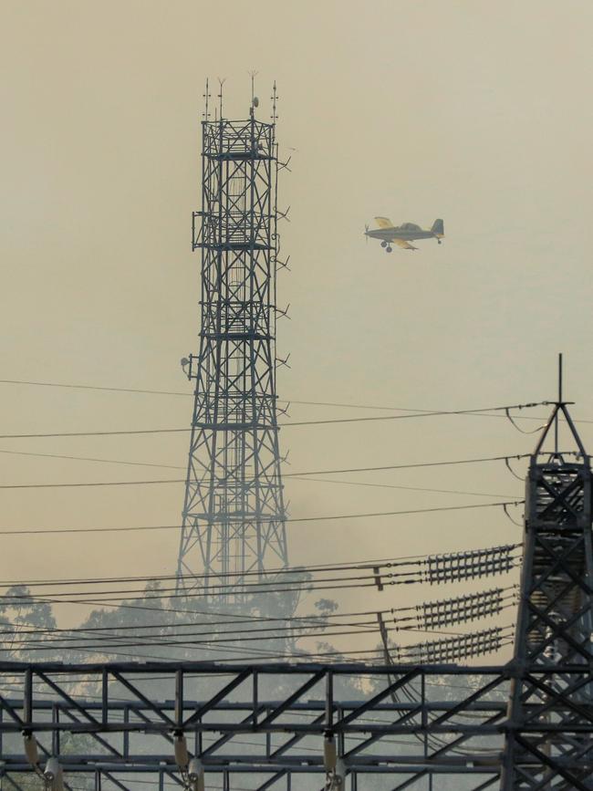 Firefighting aircraft and Firefighters defend Power infrastructure from an out of control fire in Berrimah. Picture: Glenn Campbell Picture: Glenn Campbell
