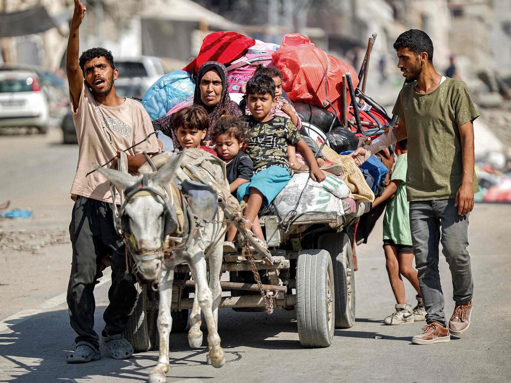 A man gestures while leading a donkey pulling a cart transporting his family members and belongings as they try to return to their home in the Tuffah district east of Gaza City on July 8. Picture: AFP
