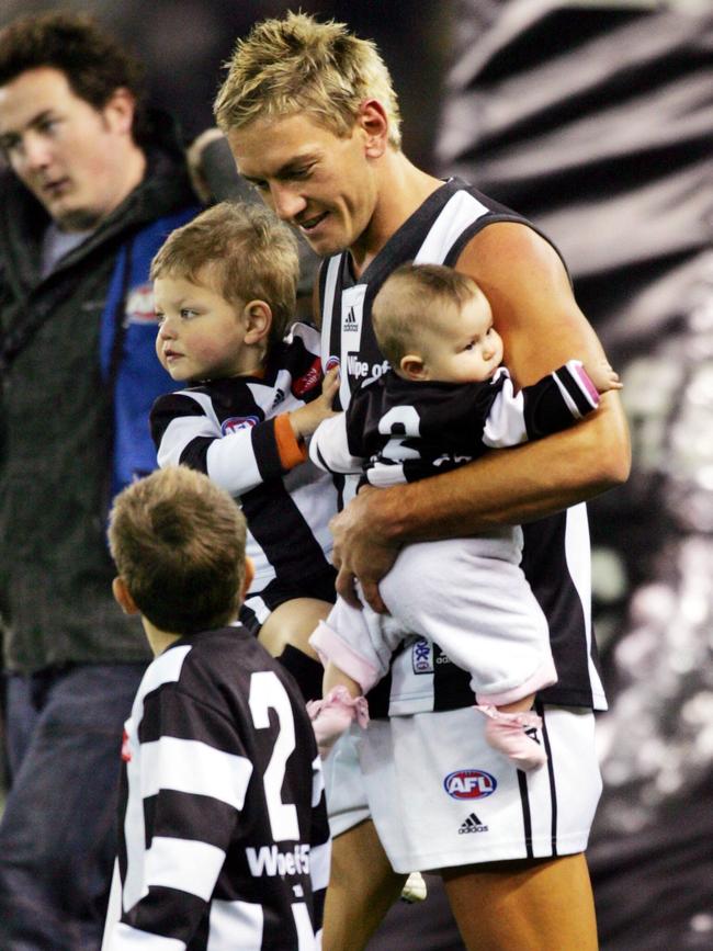 Shane Woewodin runs out with his children (Taj in his right arm) for Collingwood in 2005