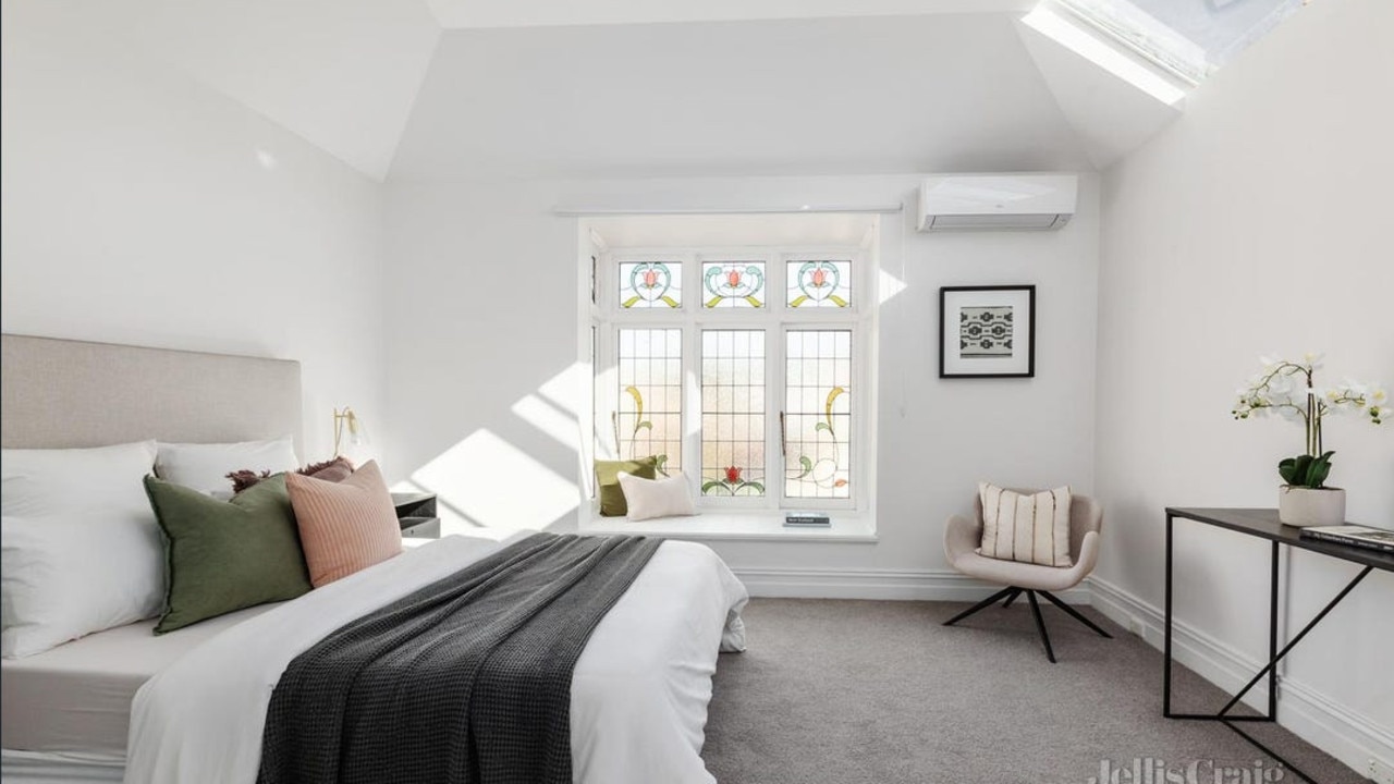 The expansive main bedroom features walk-in robes and a stained-glass window feature.