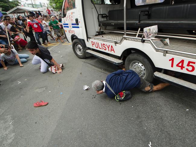 Protesters lie on the ground after being hit by a police van during a rally in front of the US embassy in Manila. Picture: Rob Reyes.