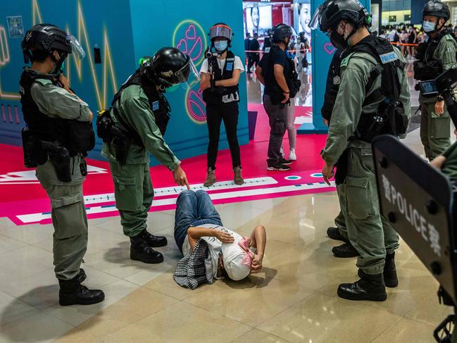 T A riot police officer (2L) points at a woman lying down after being searched during a demonstration in a mall in Hong Kong. (Photo by ISAAC LAWRENCE / AFP)