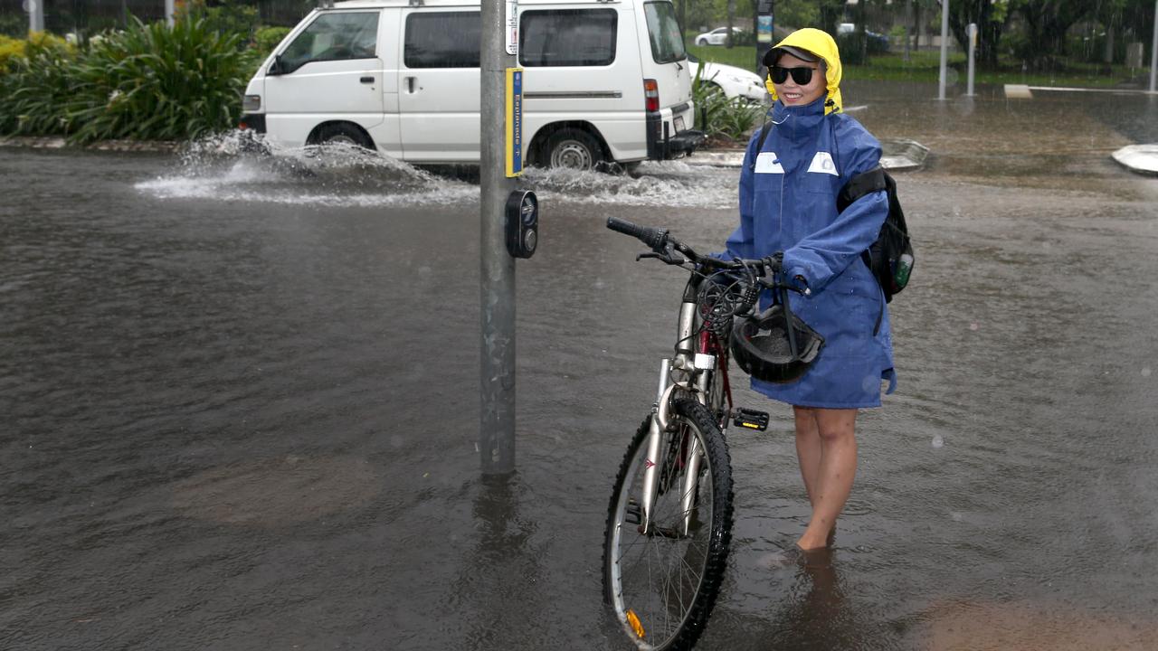 Yuka Doto rides her bike to work in the pouring rain down a flooded Spence St at the Reef Fleet terminal . PICTURE: ANNA ROGERS