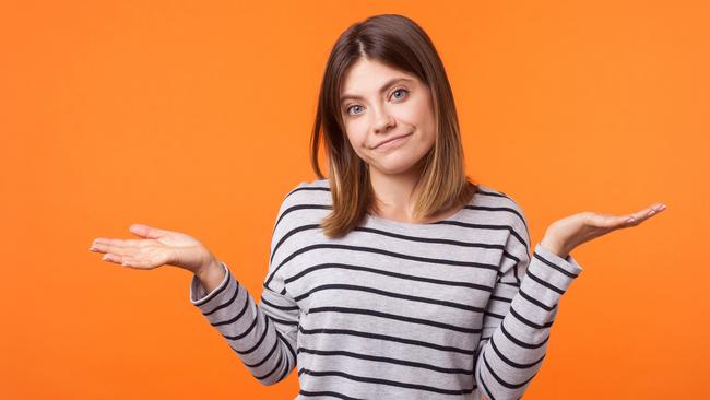 Don't know! Portrait of uncertain confused brunette woman in long sleeve shirt standing having doubts while raised hands, clueless facial expression. indoor studio shot isolated on orange background