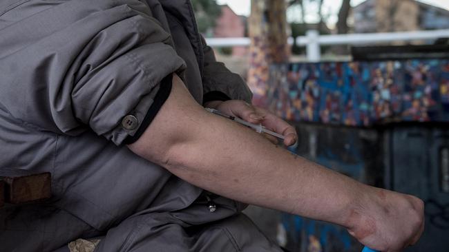 A man uses a needle near the North Richmond public housing towers. Picture: Jake Nowakowski