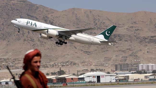 A Taliban fighter stands guard as a Pakistan International Airlines plane, the first commercial international flight to land since the Taliban retook power in 2021, takes off with passengers onboard at the airport in Kabul.