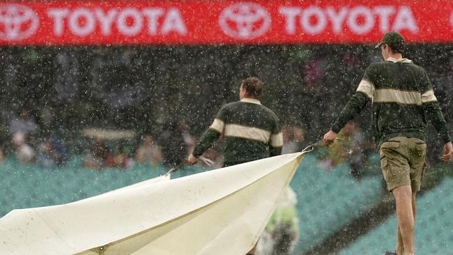 Groundsmen cover the pitch during a shower at the SCG. Up to 45mm is predicted on Saturday.