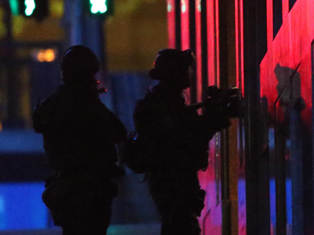 Armed tactical response officers enter Lindt cafe building after shots were fired. Picture: Rob Griffith (AP)