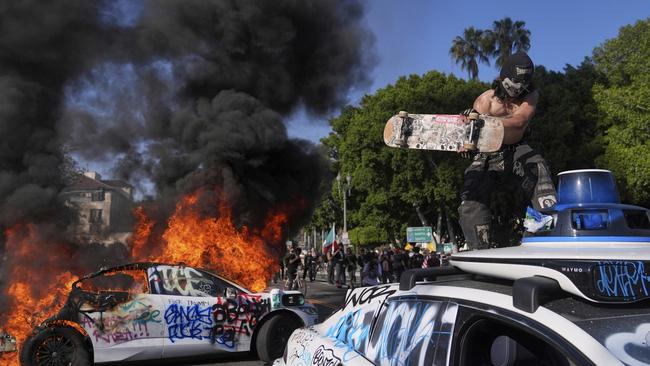 A Waymo is vandalised while another burns near the metropolitan detention centre of downtown Los Angeles. Picture: AP.