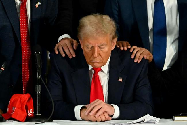 Former US president Donald Trump prays during a roundtable discussion with Latino community leaders in Florida