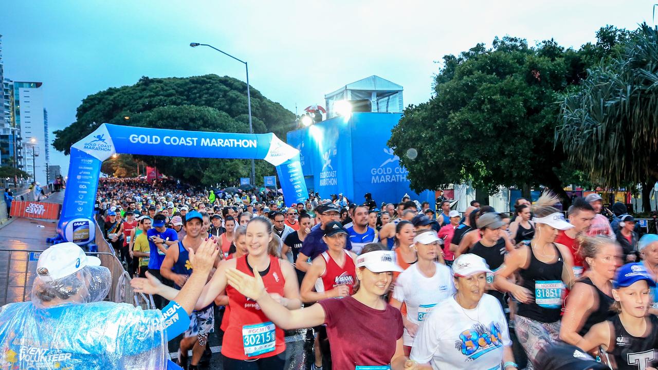 A race volunteer high-fives runners at the start of the Southern Cross University 10 kilometre Run. Picture: Tim Marsden.