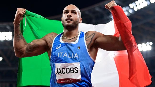 Italy's Lamont Marcell Jacobs celebrates with the flagof Italy after winning the men's 100m final during the Tokyo 2020 Olympic Games at the Olympic Stadium in Tokyo on August 1, 2021. (Photo by Javier SORIANO / AFP)