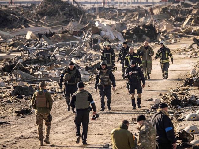 Ukrainian firefighters and servicemen walk amid the rubble of the Retroville shopping mall. Picture: AFP