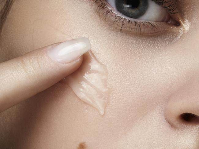 close up shot of a beautiful young woman with perfect skin applying collagen gel with her finger on her skin