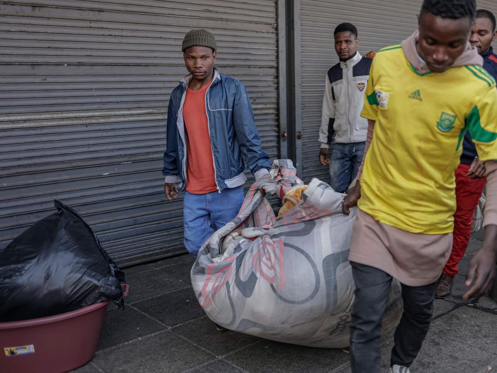 Residents carry their belongings in a blanket after the fire ripped through the residential block. (Photo by Michele Spatari / AFP)