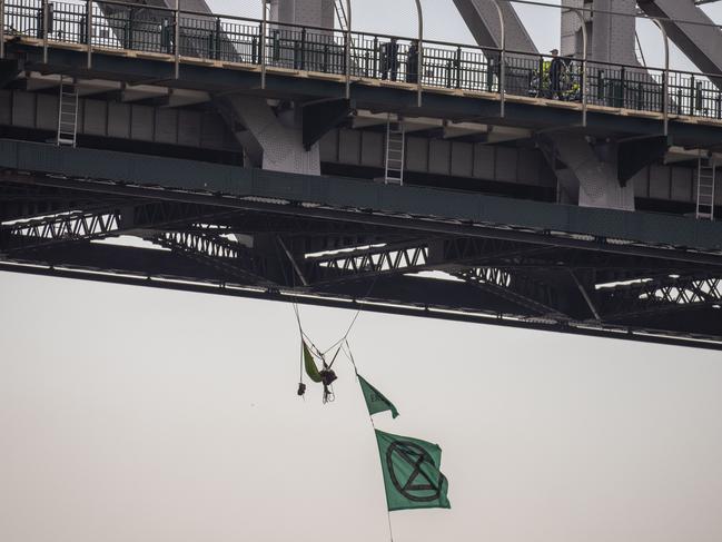 An activist from Extinction Rebellion dangles from the Story Bridge in a hammock as part of protests in Brisbane in 2019. Picture: AAP Image/Glenn Hunt