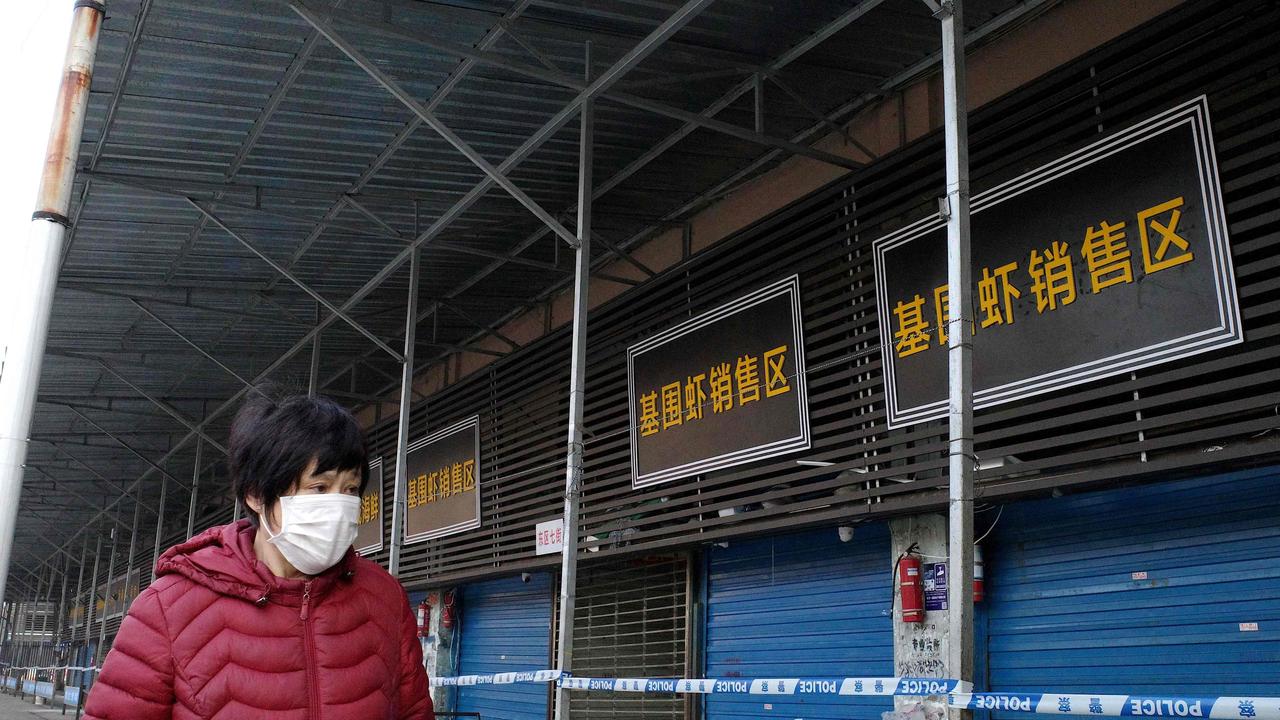 A woman walking in front of the closed Huanan wholesale seafood market, where a man who died from a respiratory illness had purchased goods from, in the city of Wuhan, Hubei province. Picture: AFP