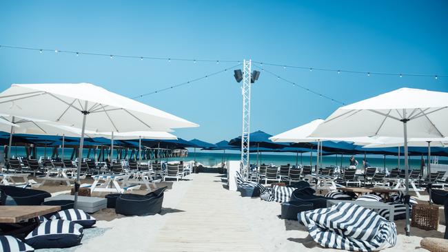 The Moseley Beach Club, beach with blue and white umbrellas and day beds.