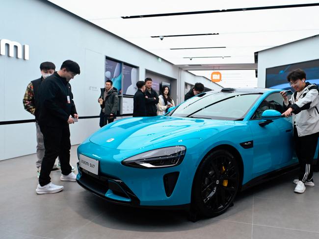 People look at a Xiaomi SU7 electric car displayed at a Xiaomi store in Beijing on March 26, 2024. (Photo by WANG Zhao / AFP)