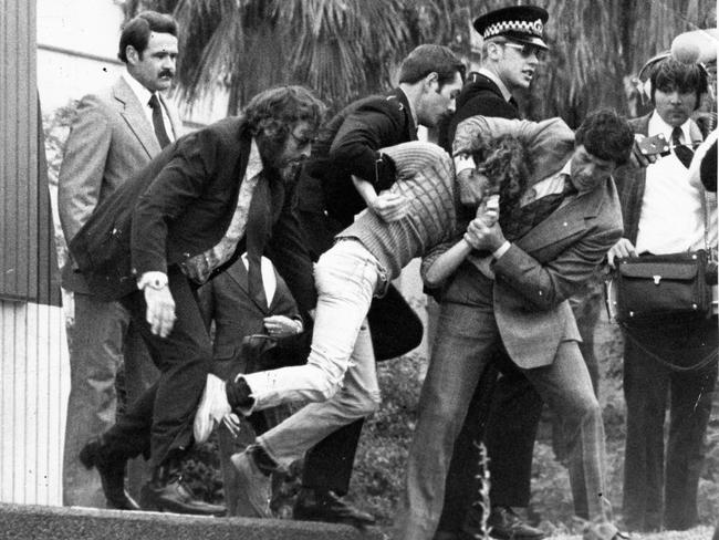 An intruder, 19, is apprehended after breaking onto official dias and waving a Eureka flag near the Queen during the opening of the Adelaide Festival Centre southern plaza and Hajek sculptures.