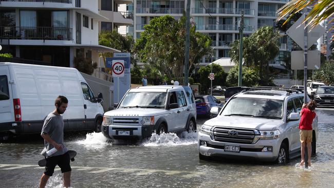 Flooding from the King tide at Budds Beach at Surfers Paradise was made worse by the approaching storm system. People wading through the floodwaters. Picture Glenn Hampson