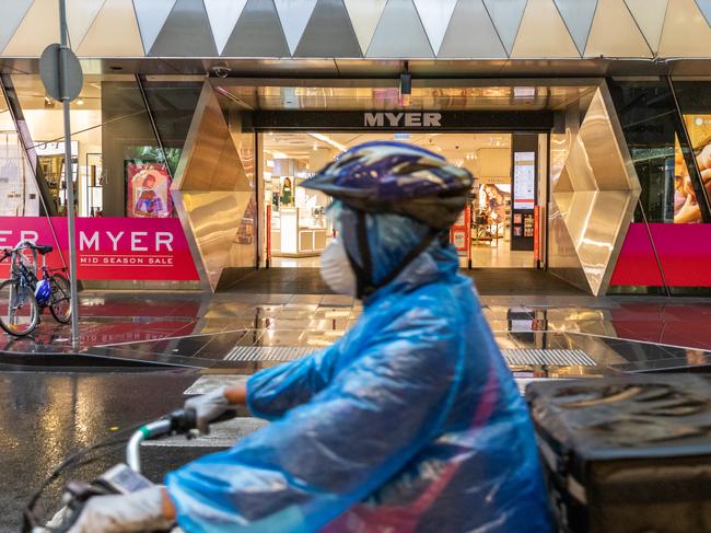 MELBOURNE, AUSTRALIA - MARCH 29: A food delivery driver wearing a face mask rides past the Myer Bourke Street department store on March 29, 2020 in Melbourne, Australia. The Australian department store announced it would be temporarily shutting down all Australian stores due to COVID-19 from Sunday until at least 27 April 2020. Around 10,000 staff will be stood down without pay during that time. Myer's closure comes as many other well known stores shut down as the coronavirus (COVID-19) outbreak and new social distancing measures take a toll on the retail industry. (Photo by Asanka Ratnayake/Getty Images)